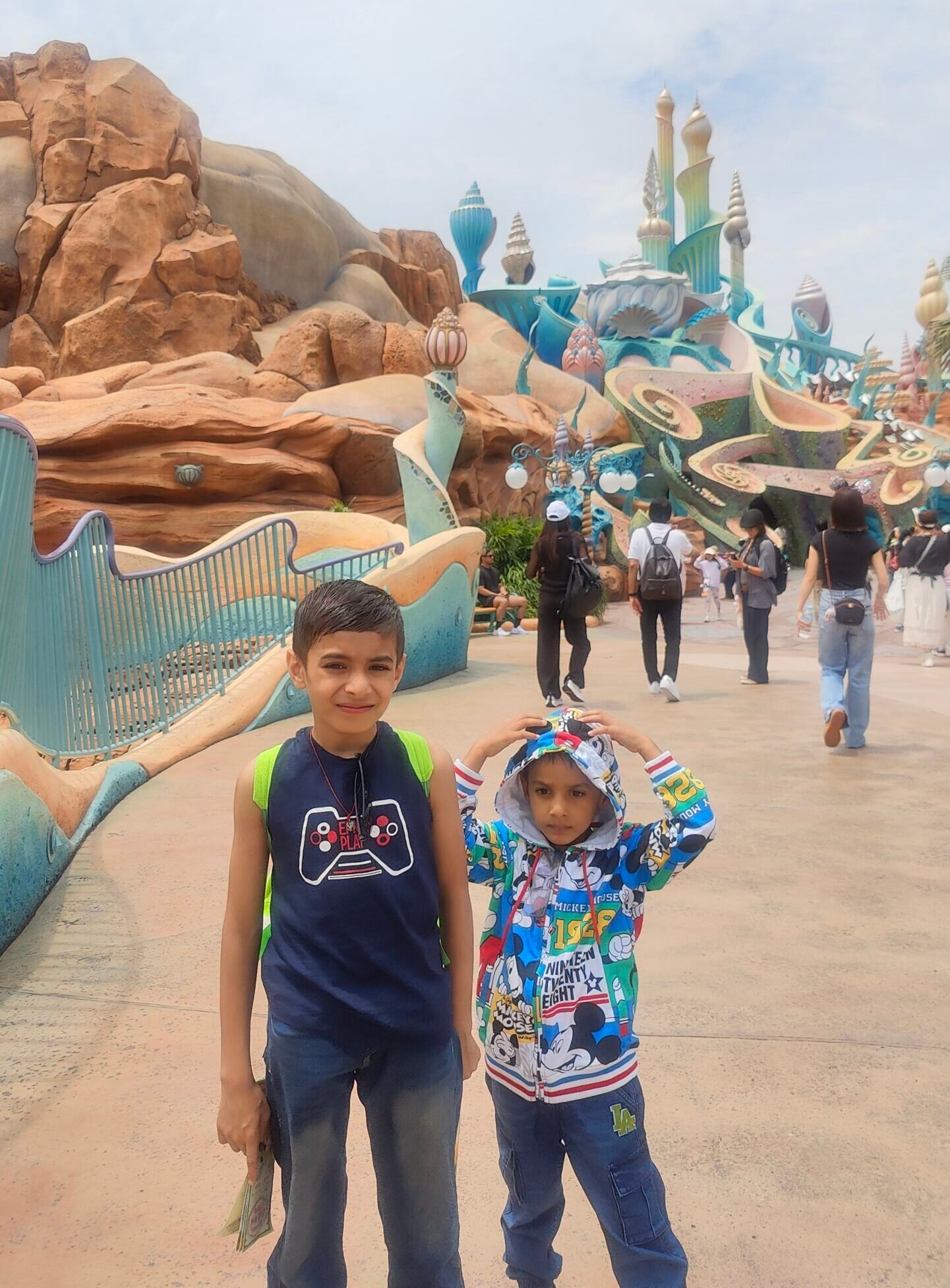 Vihaan and Mehaank standing together on a walkway in front of a whimsical blue fantasy structure