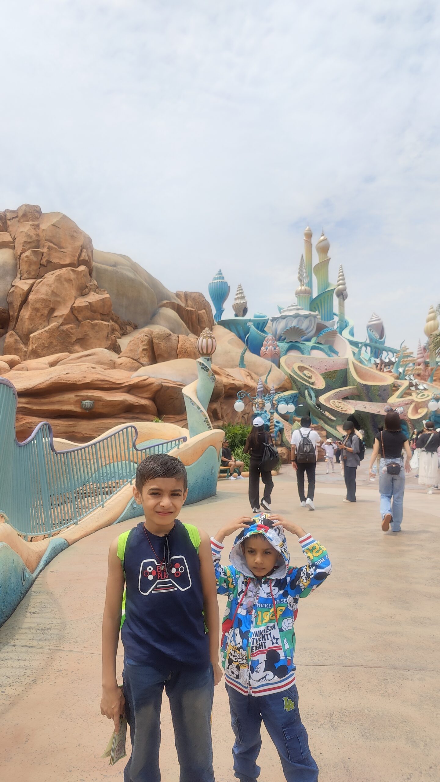Vihaan and Mehaank standing together on a walkway in front of a whimsical blue fantasy structure