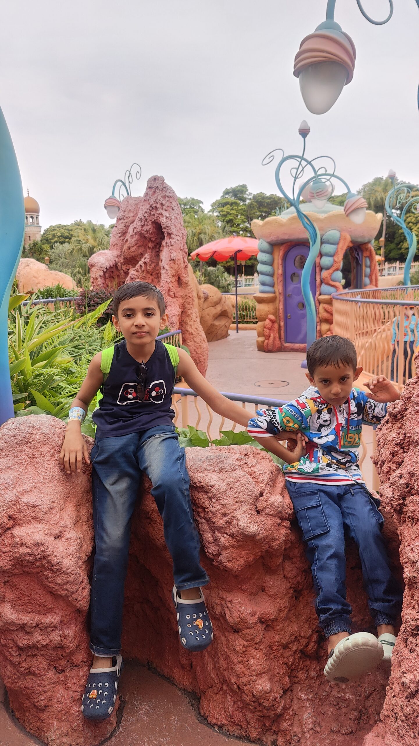 Vihaan and Mehaank posing together at a colorful theme park play area