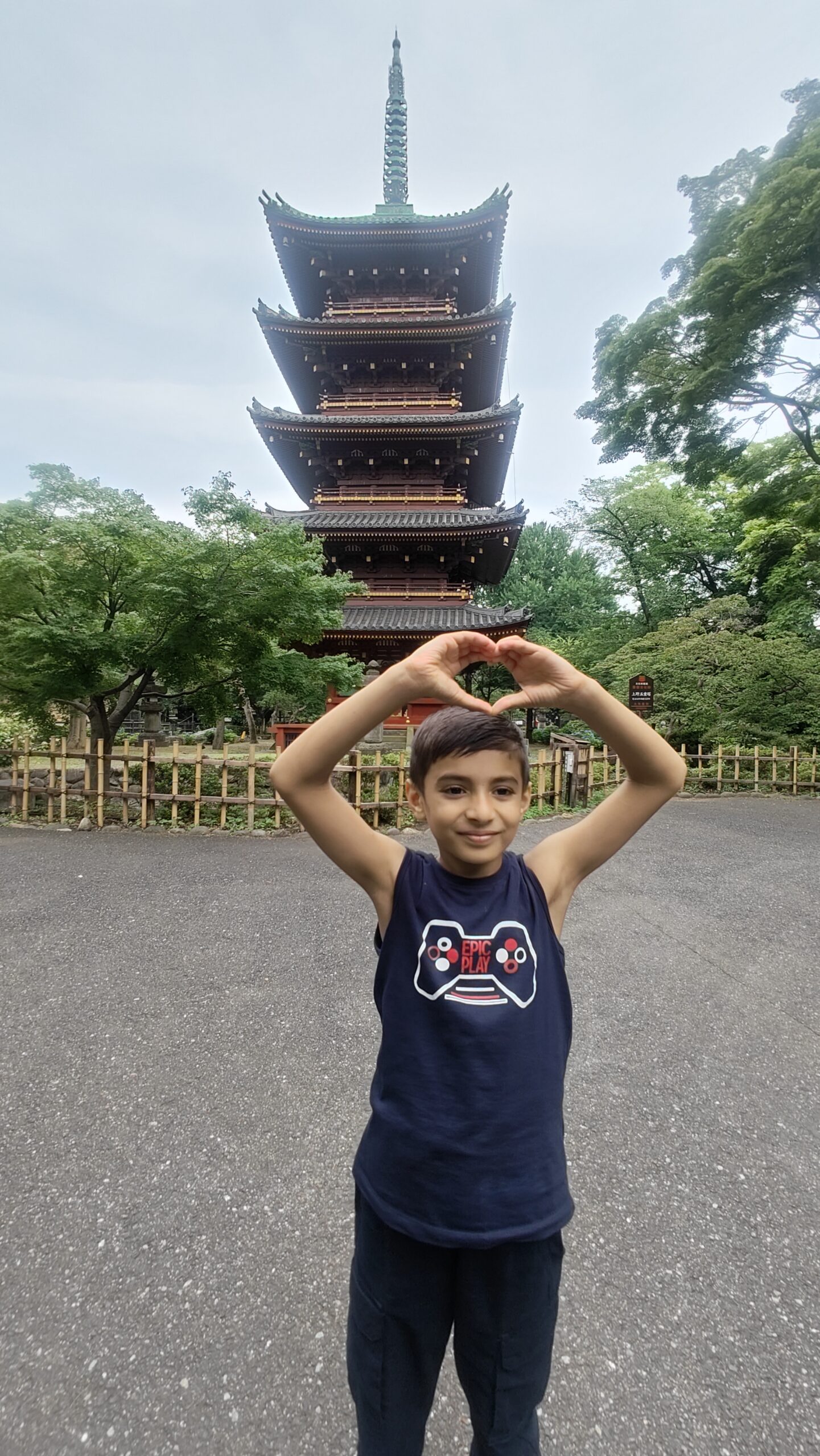 Vihaan making a heart shape with his hands in front of a traditional pagoda